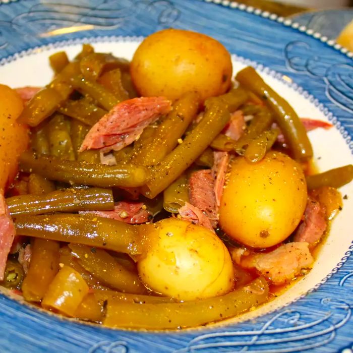 Close-up view of a bowl filled with Green Beans, Ham, and Potatoes in a blue and white patterned dish.