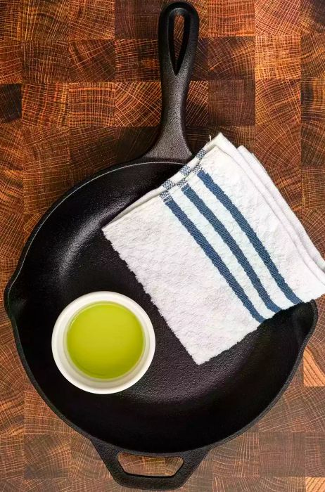 Cast Iron Skillet, towel, and oil resting on a kitchen counter