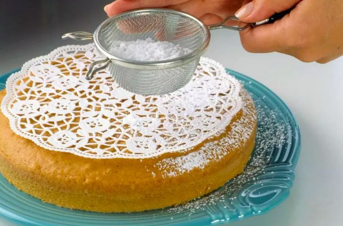 Decorating a cake with powdered sugar using a paper doily