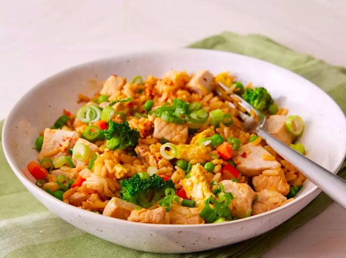 A bowl of delicious pork fried rice topped with sliced scallions.