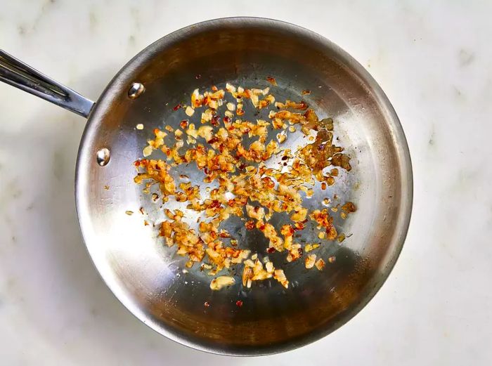 Bird's-eye view of chopped shallots cooking in a skillet.