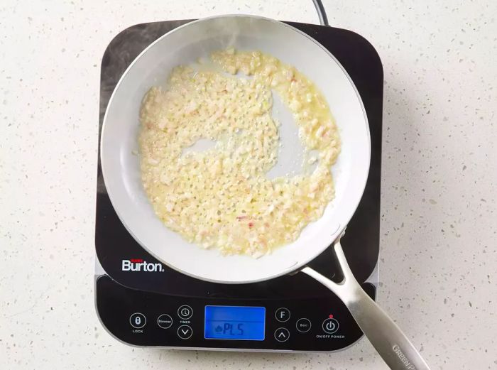 A pan with chopped shallot cooking in melted butter.