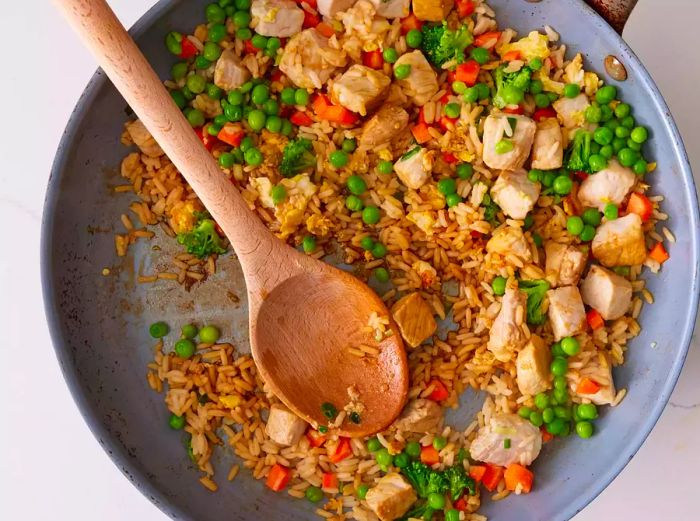 A large pan filled with pork fried rice.