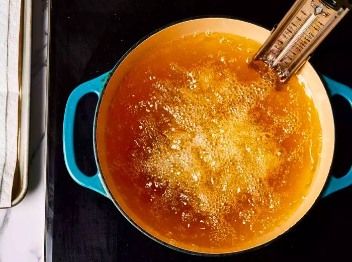 A large pot filled with sizzling catfish fillets frying in hot oil.