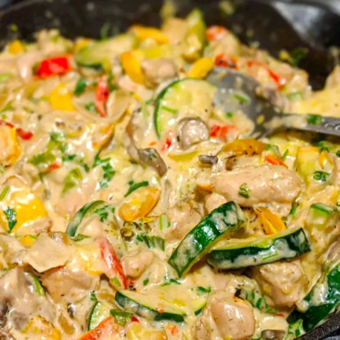 Close-up shot of Chicken with Mushrooms and Zucchini in a Creamy Sauce served in a pan with a spoon