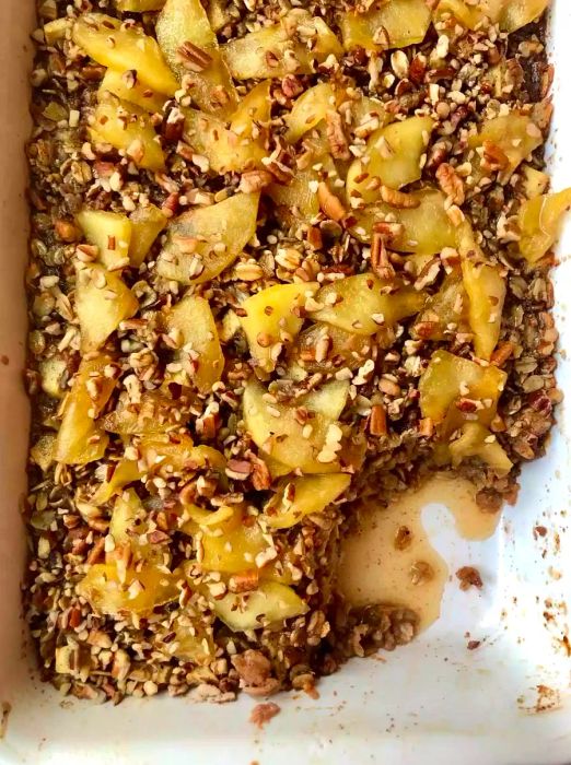 A top-down shot of a baking dish filled with baked oatmeal and garnished with fresh apple slices