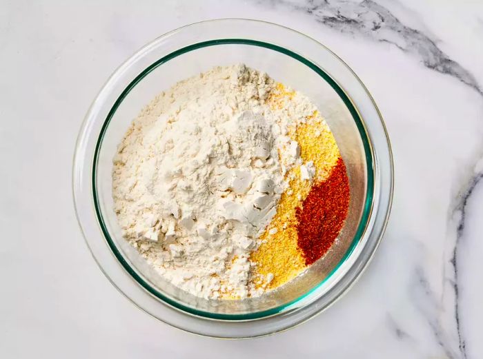 A bowl filled with a mixture of flour, cornmeal, and seafood seasoning.