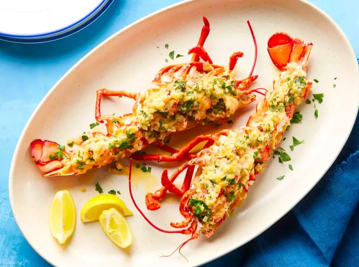 A platter of lobster thermidor, garnished with lemon wedges and sprinkled with chopped parsley.