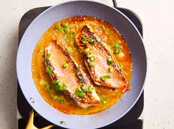 Marinade poured into the skillet, simmering until the fish flakes easily.