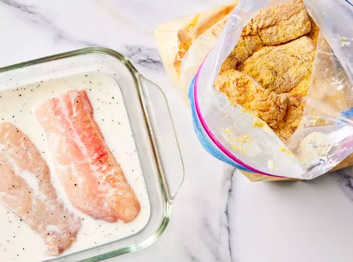 A large ziplock bag filled with seasoned cornmeal and flour, containing dredged catfish fillets.