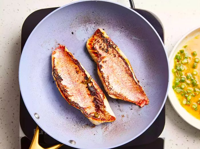 Snapper cooked in the skillet until opaque and lightly browned.