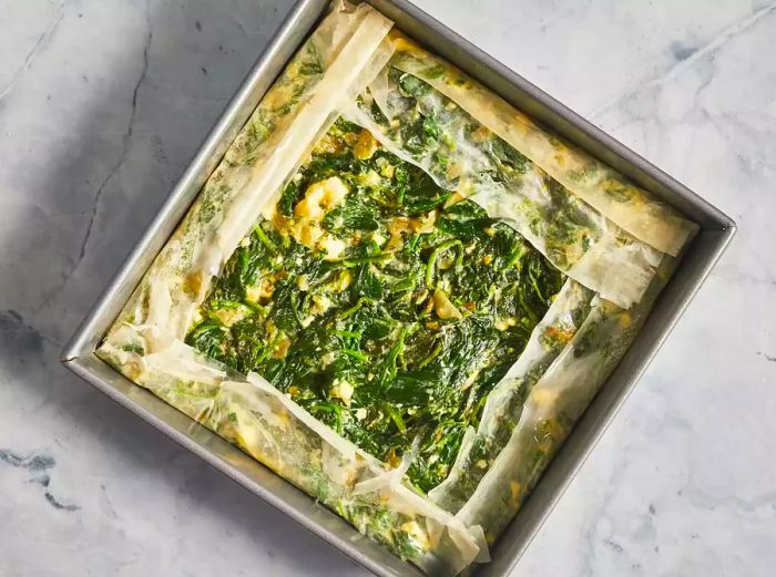 Spinach mixture spread across the pan with the excess dough folded over the top.