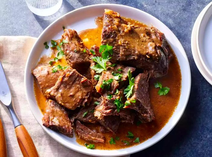 A serving dish of three-packet slow cooker roast, garnished with fresh parsley