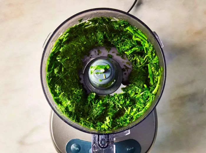 A food processor containing coarsely chopped spinach