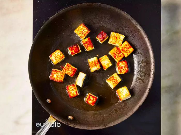 A skillet with golden-brown cubes of paneer