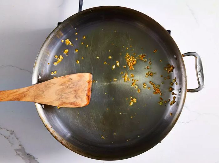 Garlic being sautéed in a pan until fragrant.