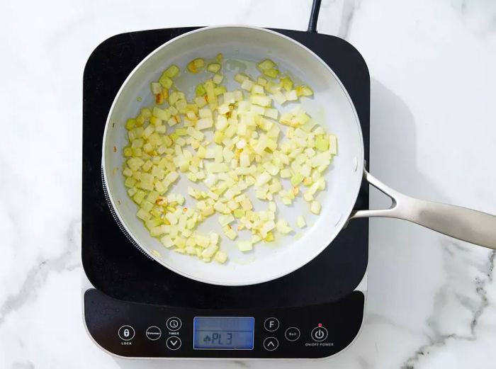 A skillet with chopped onions sizzling in oil