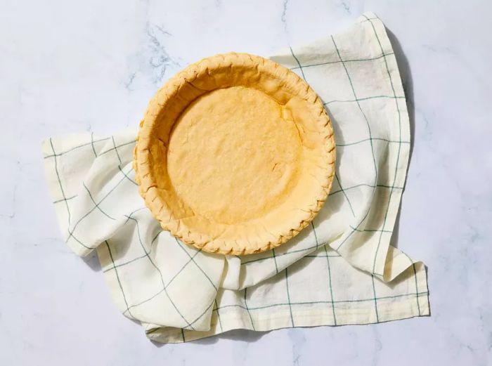 A partially baked pie crust resting on a kitchen cloth