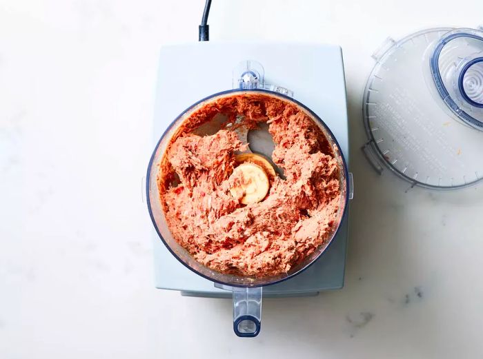 A food processor containing finely chopped, seasoned ground meat