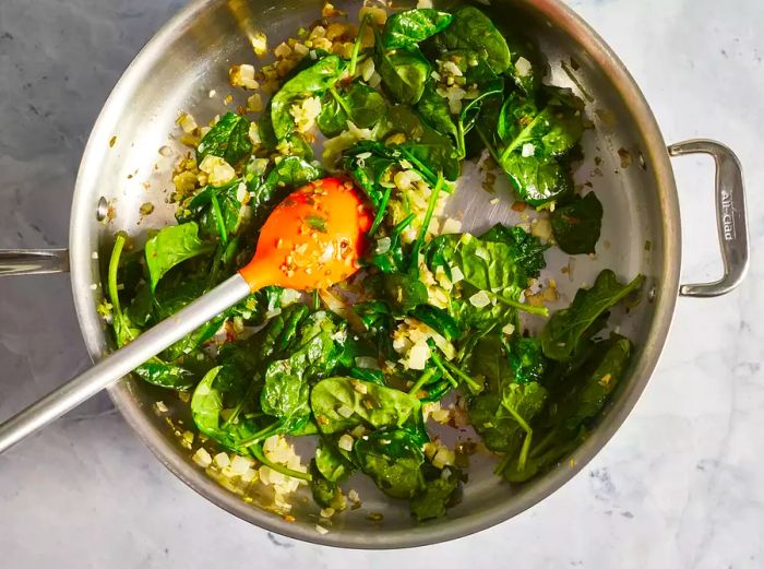 Spinach stirred into the onion and garlic mixture.