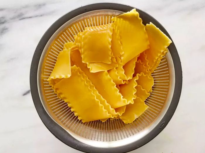 A colander filled with freshly drained lasagna noodles