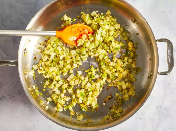 Chopped onion, green onions, and garlic sautéing in hot oil until tender and golden brown.