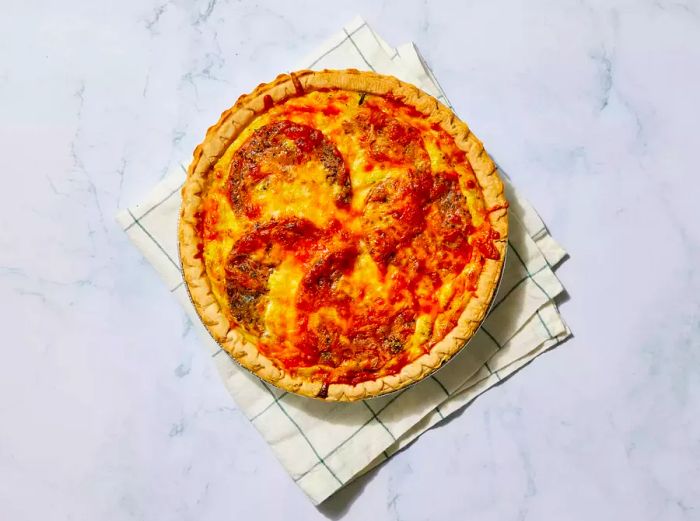 A freshly baked loaded vegetarian quiche resting on a kitchen towel