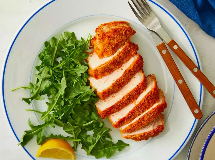 A top view of a sliced air fryer pork chop, served with a side of fresh greens