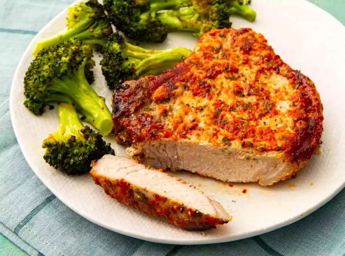 Mid-angle shot of a plate with sliced pork chops and a side of broccoli