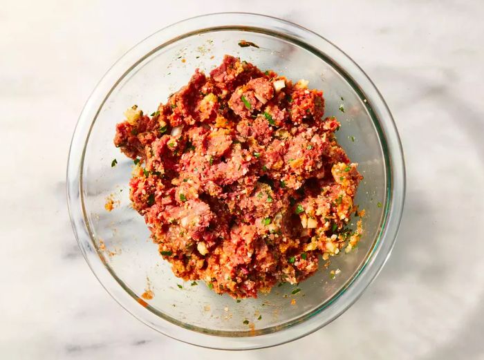 A glass bowl containing the meat mixture for Low-Carb Meatloaf with Pork Rinds