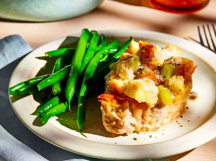 Plated stuffed pork chop served with green beans on the side.