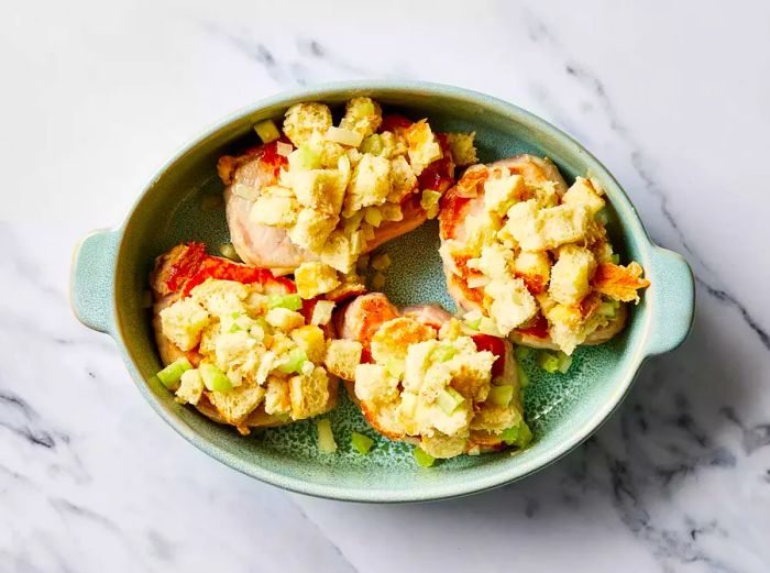 Stuffed pork chops filled with bread cubes and celery, placed in a baking dish.