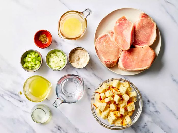 Ingredients for stuffed pork chops arranged on a marble countertop.