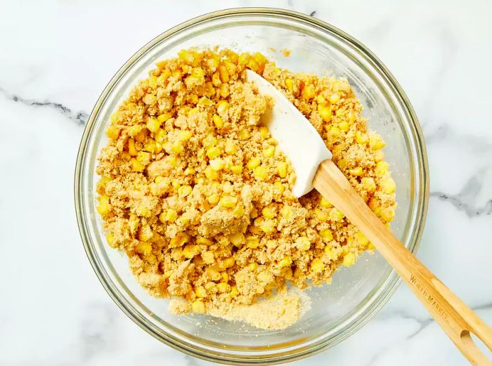 Corn, bread crumbs, egg, and butter mixed together in a bowl.