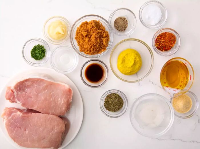 All ingredients for the Best Pork Chop Marinade neatly arranged in small bowls on a marble countertop.