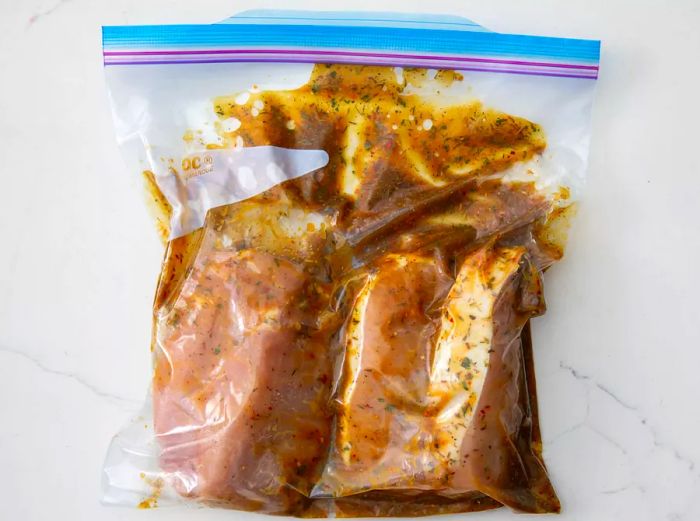 Pork chops and marinade inside a ziplock bag, ready to marinate.