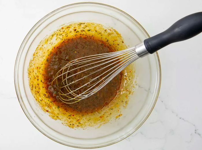 The ingredients for the Best Pork Chop Marinade combined in a clear mixing bowl.