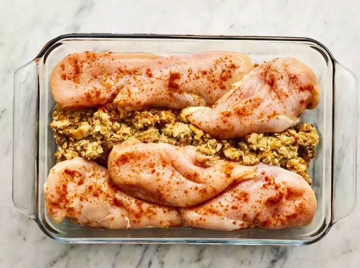 Stuffing placed in the center of the baking dish with chicken arranged around it, and a sprinkle of paprika on top.