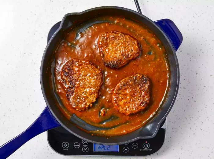 Beef bouillon and salt added to the skillet, simmering until the meat becomes tender and flavorful.