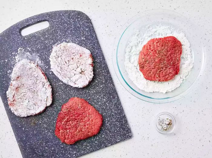 Cube steaks seasoned with salt and pepper, then gently coated in flour in a shallow dish.