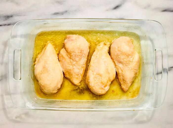 A baking dish with four perfectly baked chicken breasts.