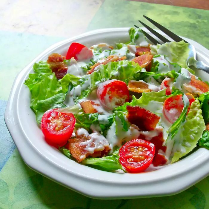 a close-up of a BLT Salad on a white plate, served with a fork