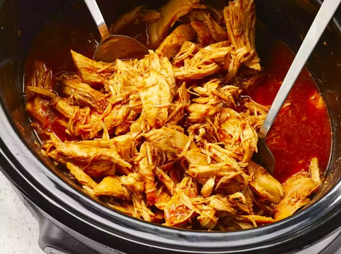 a top-down view into a slow cooker filled with chicken barbecue