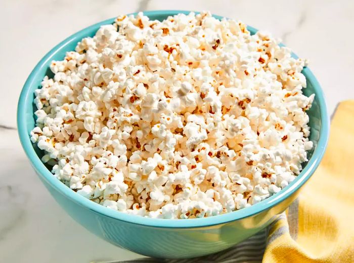 A high-angle shot of a blue bowl filled with fresh microwave popcorn.