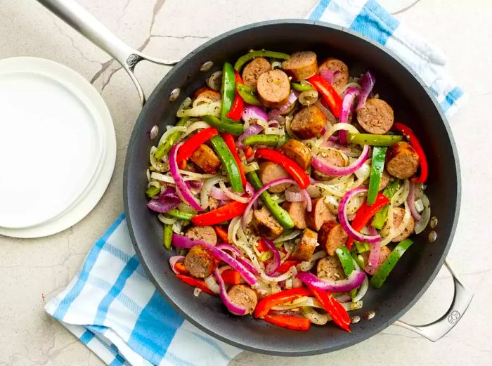 a top-down shot of a skillet filled with Italian sausage, peppers, and onions