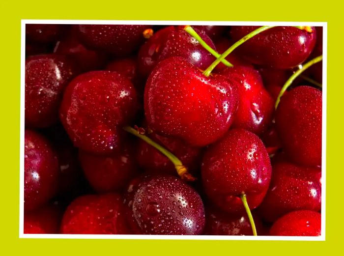 A close-up image of cherries with droplets of water on their surface.