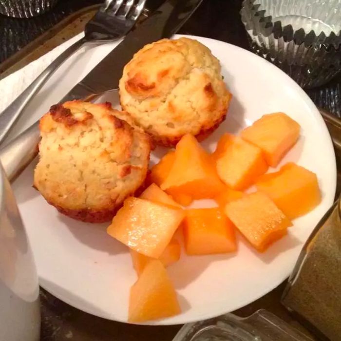 muffins served on a plate with cantaloupe slices