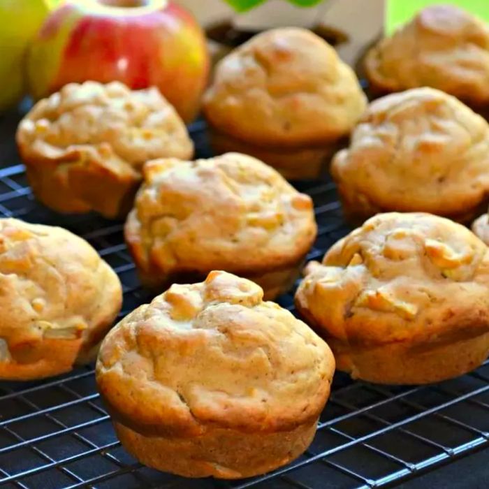 muffins cooling on a rack with apples placed nearby