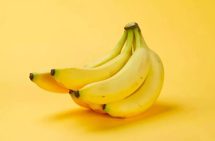 A bunch of ripe yellow bananas on a yellow background