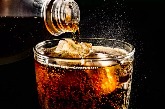 Close-Up Of Drink Pouring In Drinking Glass Against Black Background